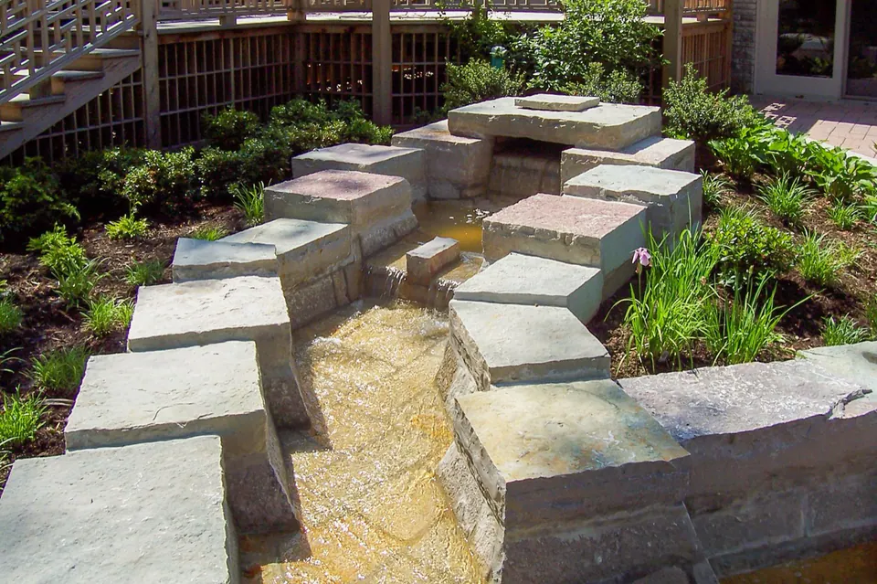 Limestone block water feature with stone treads and low garden planting